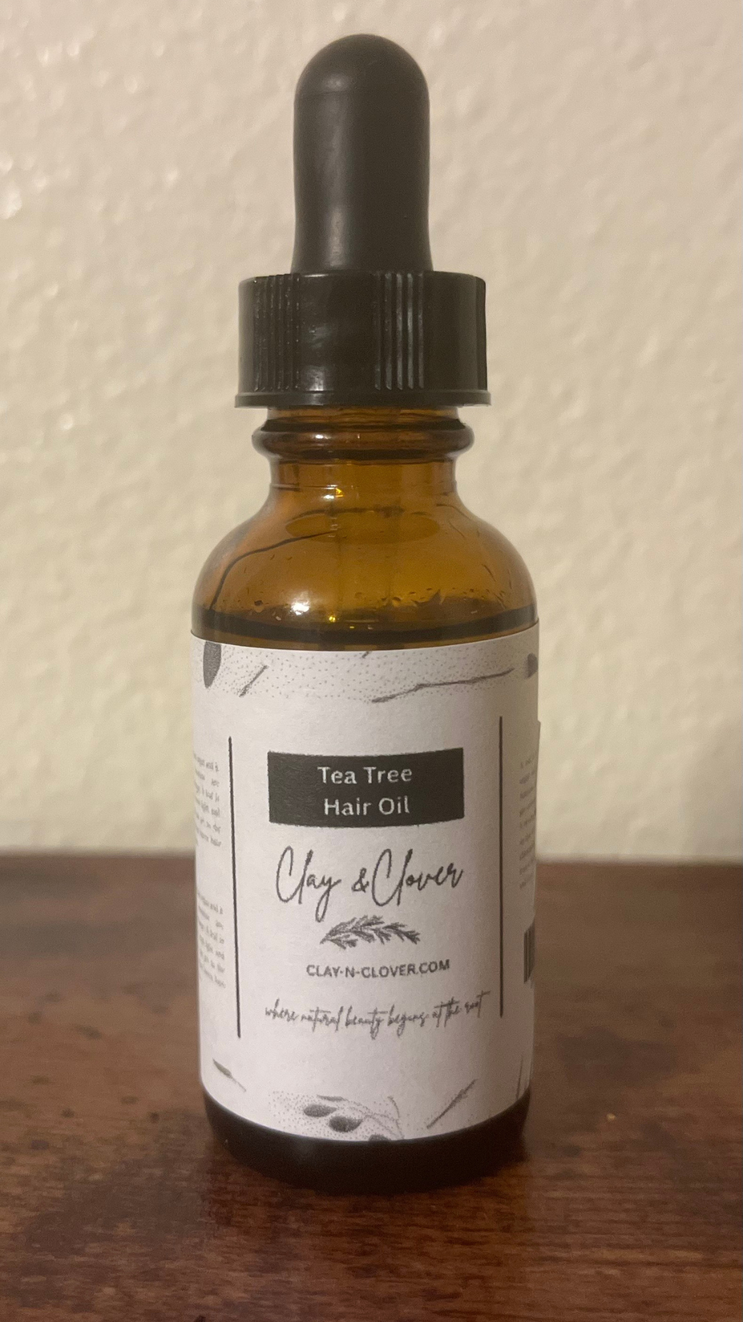 “Clay-N-Clover Tea Tree Hair Oil in amber bottle — natural scalp treatment infused with tea tree, olive oil, and vitamin E for soothing, healthy hair growth.”